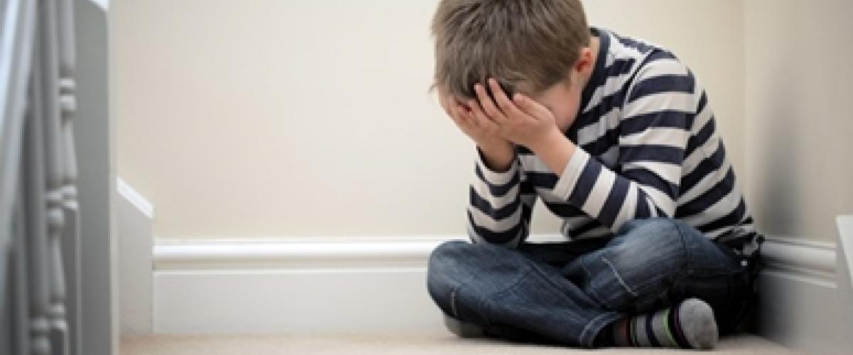 little boy sitting on the floor covering his face