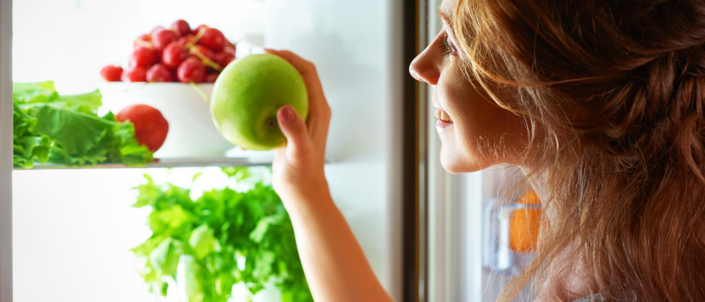 teen girl looking into fridge at healthy food