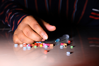 close up image of a hand surrounded by pills and drug para